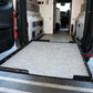 Van interior with a deployed storage ramp labeled Camper Adventure Vans