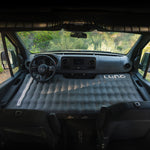 Inflatable mattress in the front of a van with 'Luno' branding.