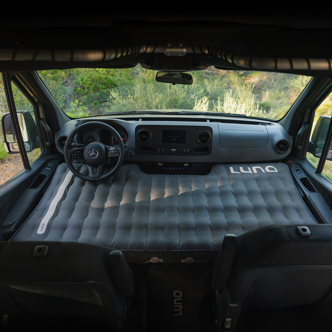 Inflatable mattress in the front of a van with 'Luno' branding.
