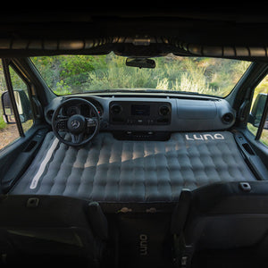 Inflatable mattress in the front of a van with 'Luno' branding.