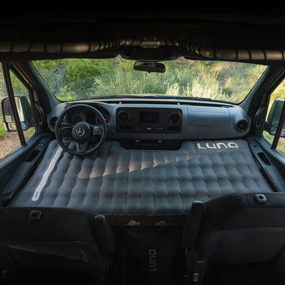 Inflatable mattress in the front of a van with 'Luno' branding.